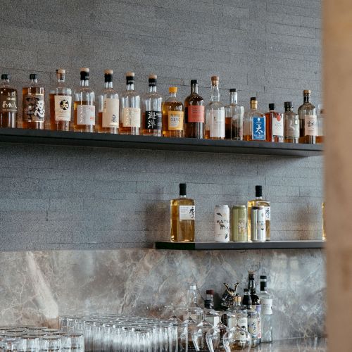 A bar display with various liquor bottles on shelves and glasses on a counter.