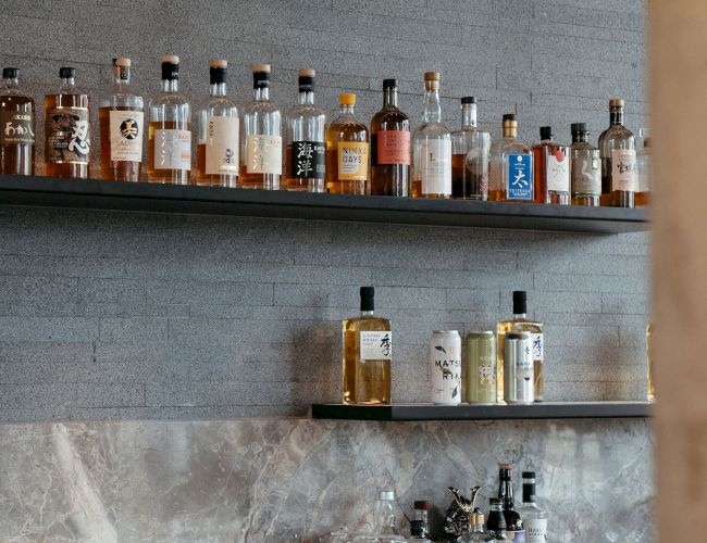 A bar display with various liquor bottles on shelves and glasses on a counter.