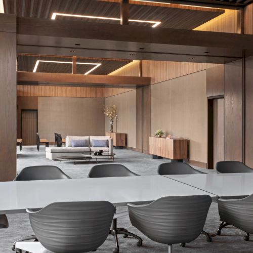A modern conference room features sleek chairs around a white table, with a sofa and minimalist decor in the background.