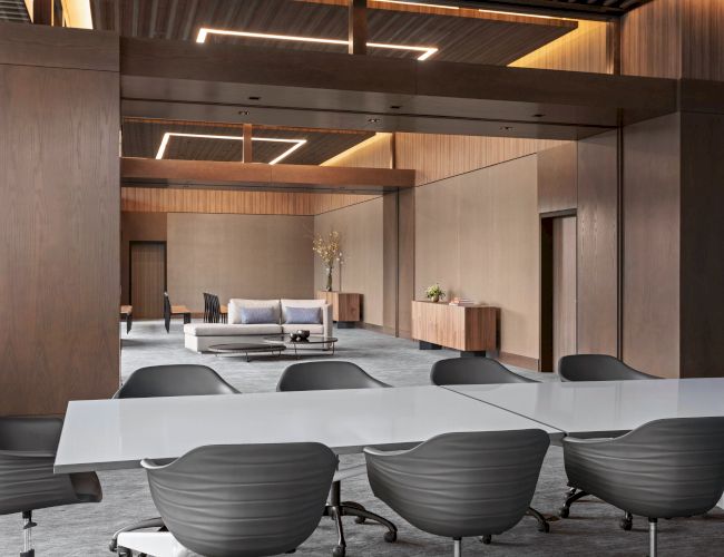 A modern conference room features sleek chairs around a white table, with a sofa and minimalist decor in the background.