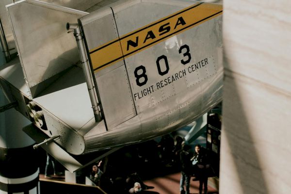 The image shows part of a NASA aircraft with the number 803 and "Flight Research Center" visible in an indoor setting.