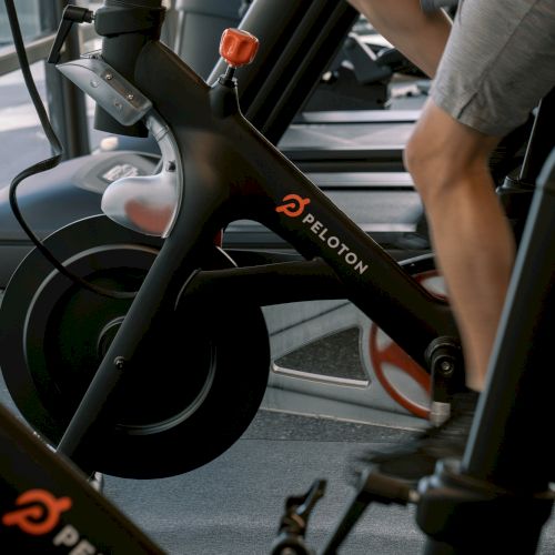 A person using a Peloton exercise bike in a gym setting.